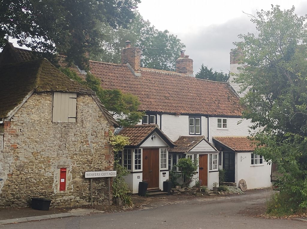 Several cozy cottages in a charming English village and a nearby red post box.